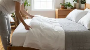 Persona che sistema con cura il letto in una camera luminosa e ordinata