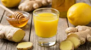 Bicchiere di shot allo zenzero con limone, miele e radice fresca su tavolo di legno