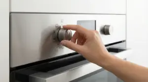 Mano che ruota una manopola su un forno moderno in acciaio inox