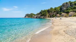 Spiaggia tranquilla con mare cristallino e poche persone in una baia rocciosa