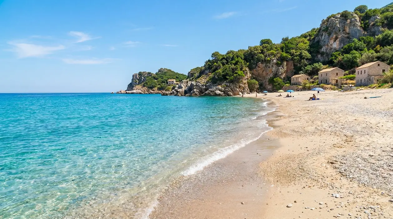 Spiaggia tranquilla con mare cristallino e poche persone in una baia rocciosa