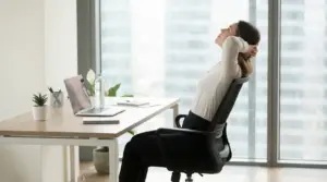 Persona seduta alla scrivania che esegue uno stretching per la schiena in ufficio