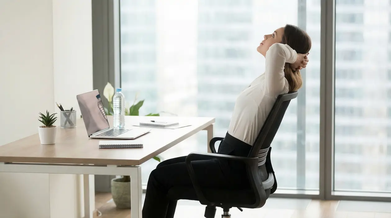 Persona seduta alla scrivania che esegue uno stretching per la schiena in ufficio